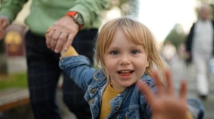 Petite fille faisant un signe de la main à la caméra.