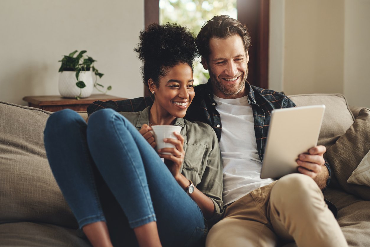 Couple using a digital tablet together while relaxing on a couch