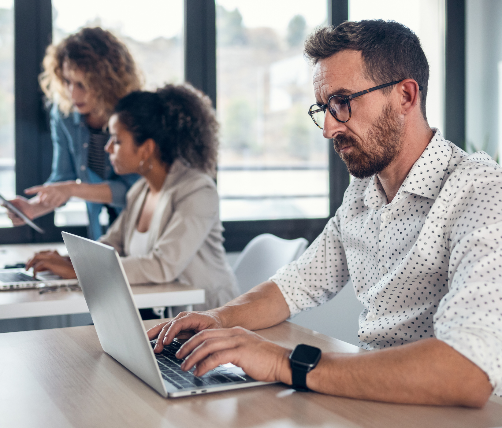 Man-working-on-laptop-in-office-with-two-women