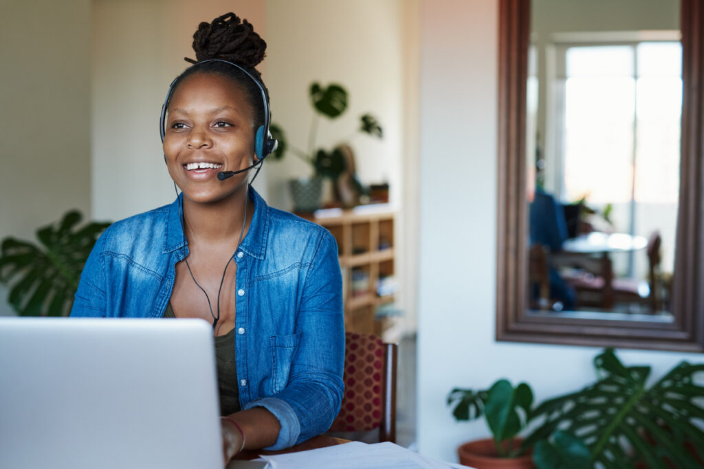 Woman on computer wearing headset smiling while working