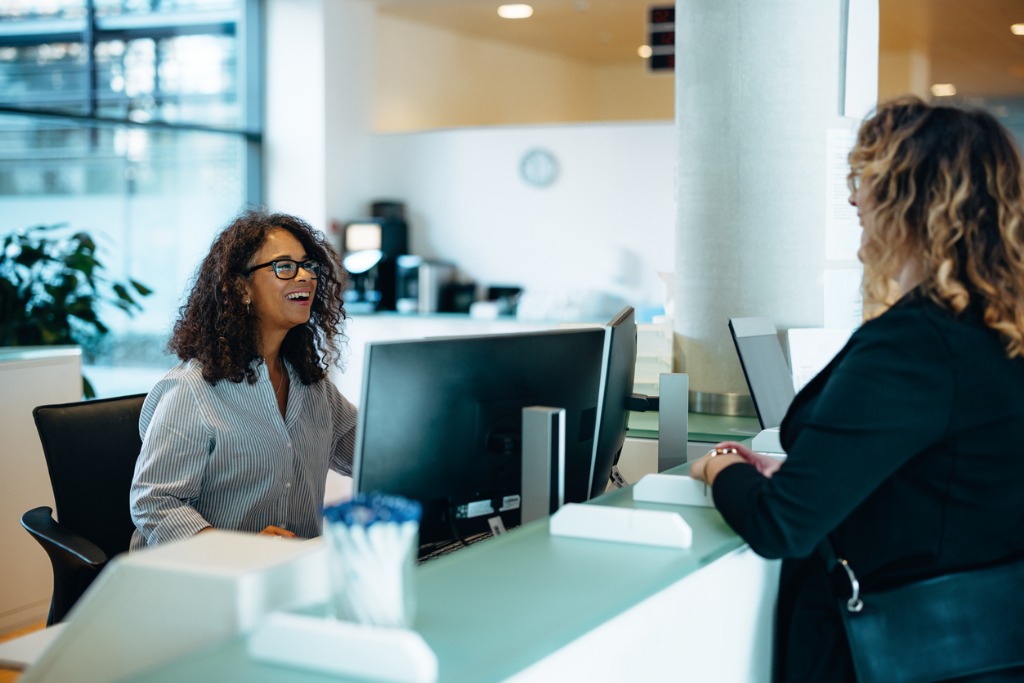 Friendly administrator assisting woman at reception of government building. 