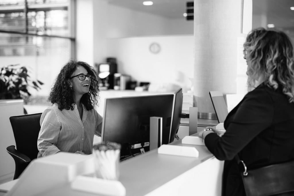 Friendly administrator assisting woman at reception desk government office municipal