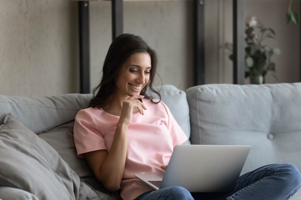 Woman smiling using laptop in her home